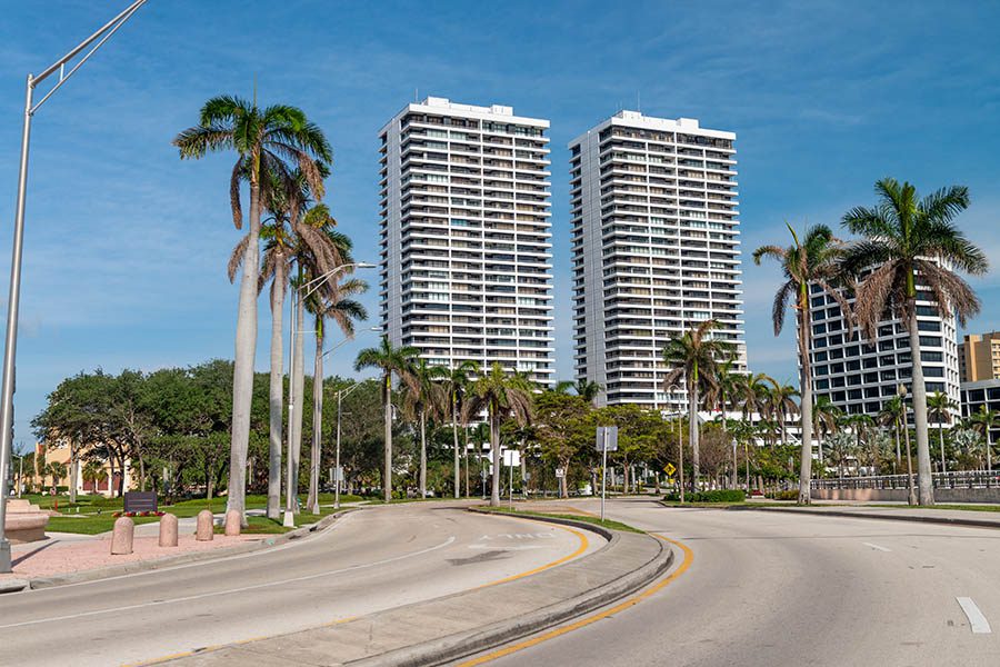 Contact - West Palm Beach Cityscape in Trinity Park, Florida Displaying Palm Trees and Tall Buildings on a Sunny Day